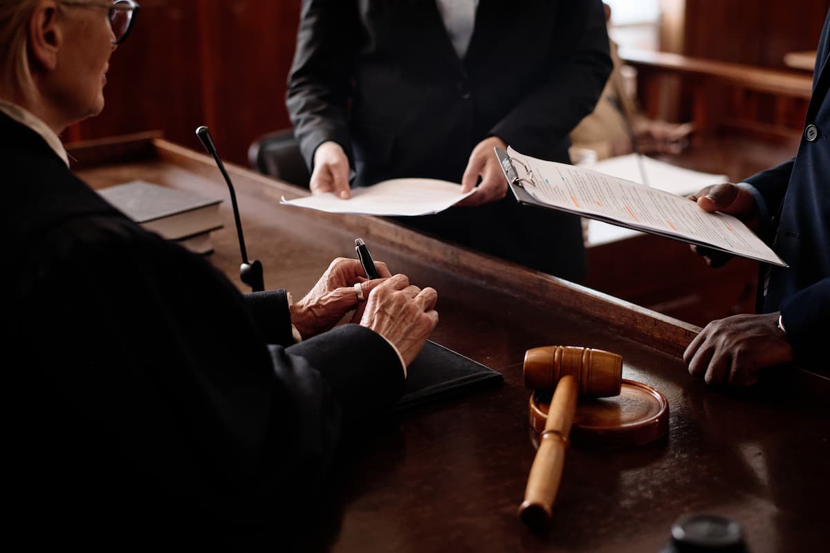 Judge reviewing documents with attorneys in a courtroom during a patent litigation expert witness proceeding.